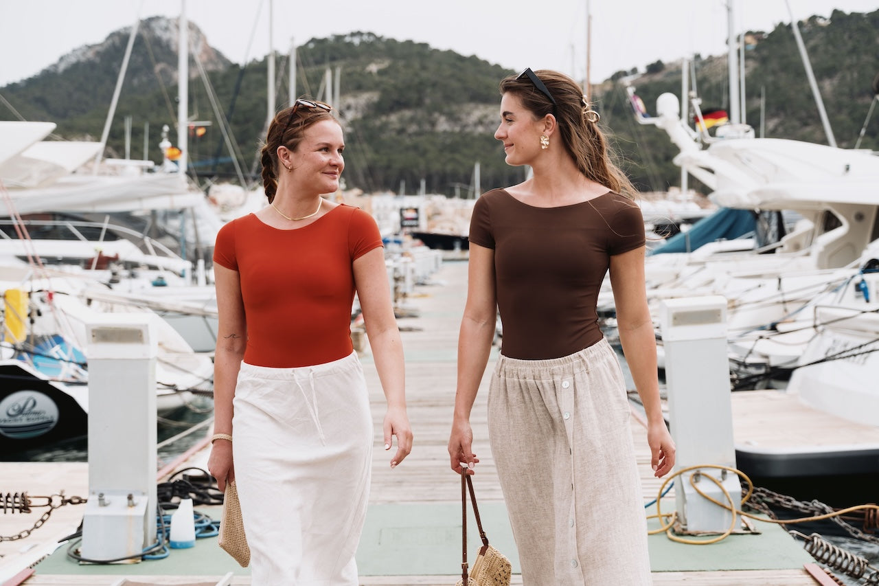 Two women walking on a dock with boats in the background