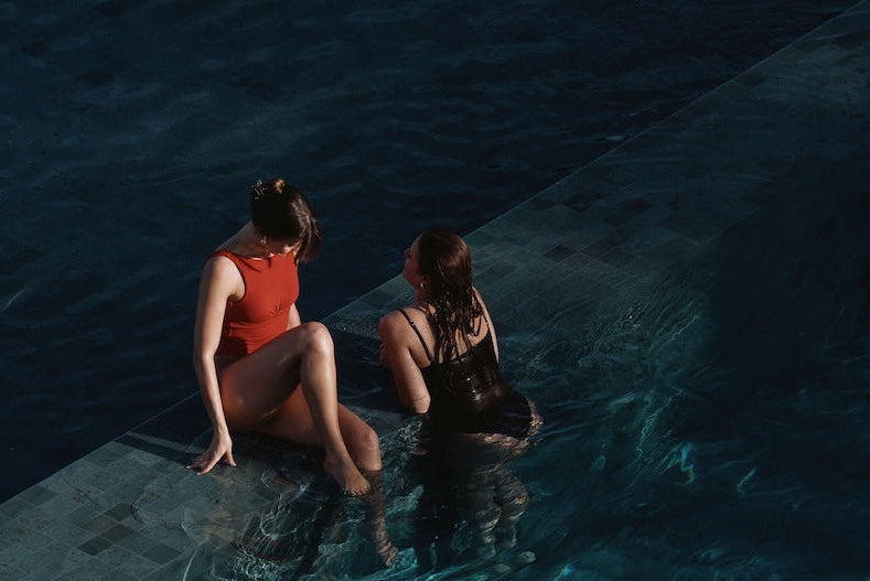 Two women sitting by a poolside at night in europe